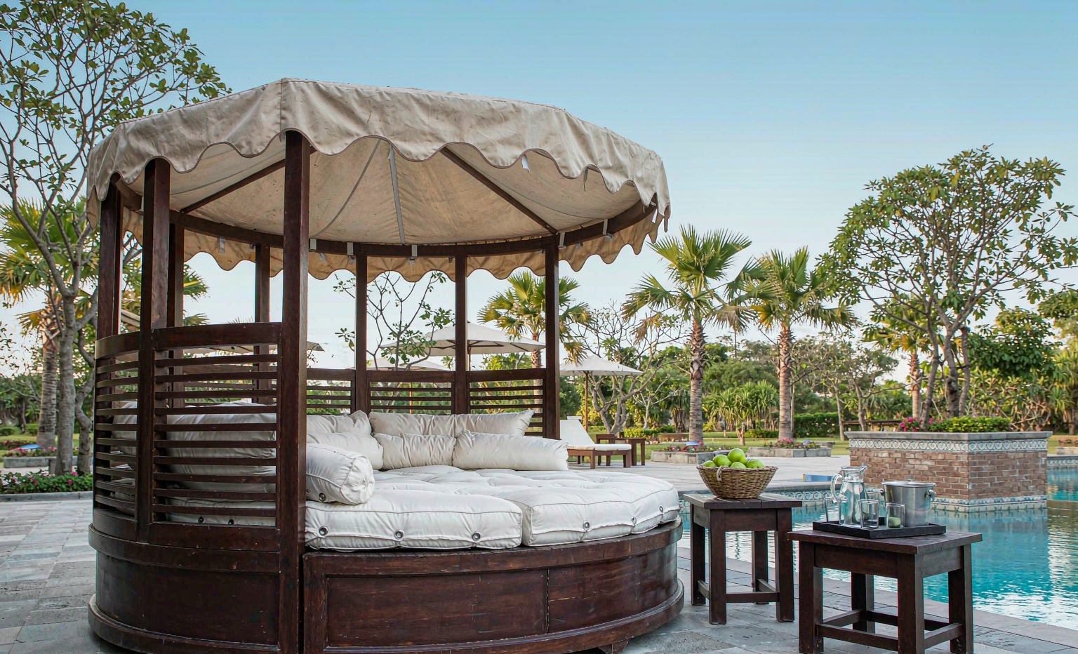 Round outdoor daybed beside a swimming pool